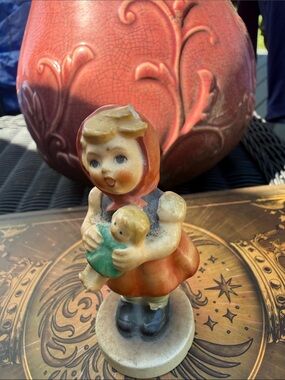 Hummel Girl Figurine in Orange Hood Holding Green Doll